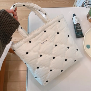 Detail of white quilted tote bag featuring black polka dots and simple wish fabric label