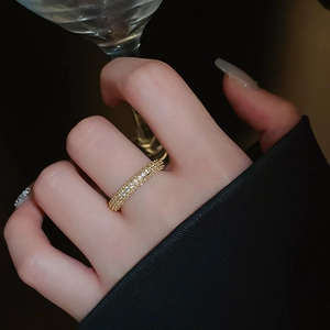 Close-up of elegant gold plated zircon pave twisted open ring on finger with glass