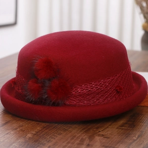 Detailed close-up of dark red wool beret featuring lace trim and rabbit fur pom-poms
