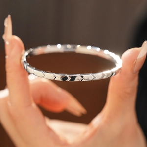 Macro shot of silver metal bangle with engraved arrow patterns on a model's wrist
