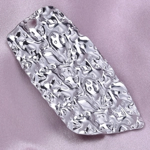 Macro detail of silver irregular crumpled pendant with metallic texture on pink satin