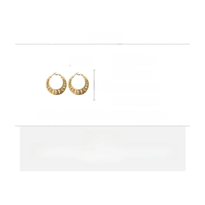 Detail view of twisted gold-plated hoop earrings with silver needles and copper material