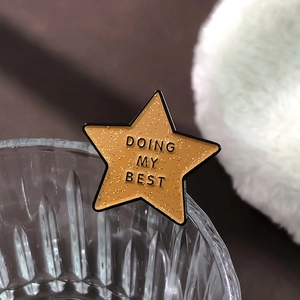 Sparkly yellow star enamel pin with Doing My Best text on a decorative glass rim