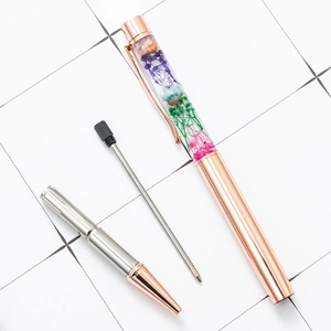 Disassembled rose gold herbarium ballpoint pen with colorful dried flowers and ink refill