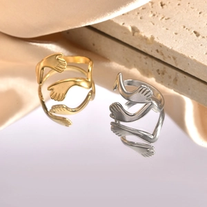 Detail view of gold and silver hug rings on reflective surface with satin fabric