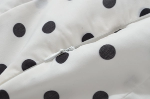 Détail du tissu de robe blanc à pois noirs et fermeture éclair invisible discrète