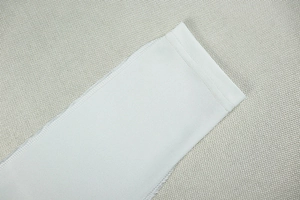 Macro view of white jumpsuit sleeve detail featuring precise stitching and fine jersey fabric