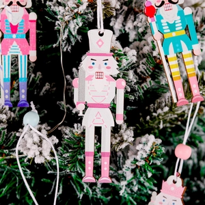 Detail of hand-painted Nutcracker wooden ornaments hanging on a snow-covered Christmas tree