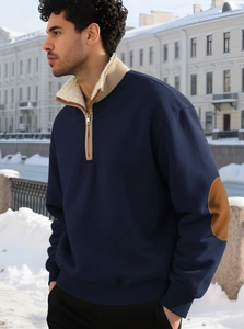 Detail of navy quarter-zip sweatshirt with beige fleece collar and brown elbow patches