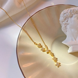 Luxurious titanium steel necklace with tassel star pendants on a beige ceramic plate