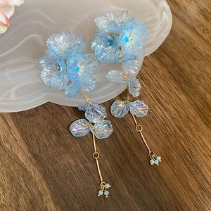 Detail of light blue floral tassel earrings with golden chain and bead accents