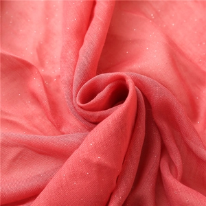 Close-up of soft coral pink fabric with shimmering glitter and subtle mesh texture