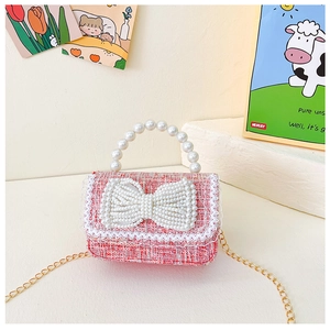 Détail d'un sac fille en tweed rose avec poignée en perles et grand nœud décoratif