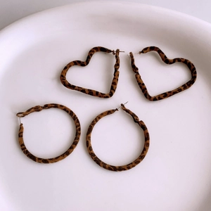Detailed view of leopard print heart and round earrings on a ceramic tray