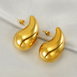 Detailed close-up of 18K gold-plated teardrop earrings resting on elegant grey silk fabric