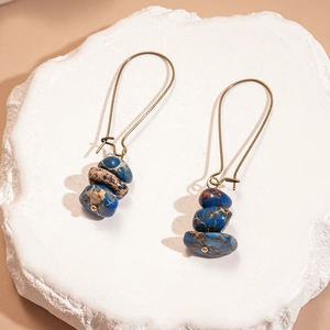 Détail de boucles d'oreilles en cuivre vintage avec pierre d'empereur bleue superposée