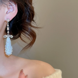 Close-up of model wearing silver bow drop earrings with sparkling zircon and teardrop charms