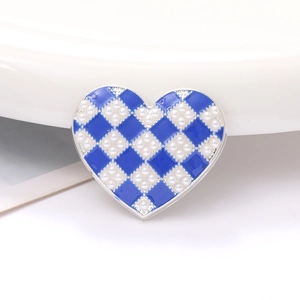 Macro detail of heart-shaped charm with blue checkerboard pattern and pearls