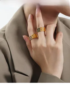 Three-layer gold titanium ring with green gemstones and diamonds shown on hand