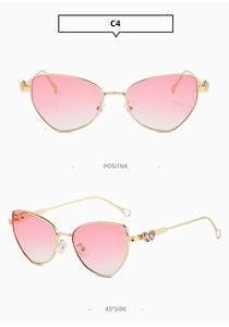 Close-up of cat-eye metal sunglasses with pink gradient lenses and heart-shaped temple gems