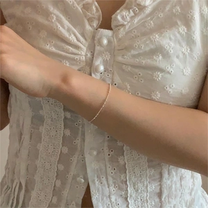 Detail of 925 sterling silver beaded bracelet on wrist over white lace background
