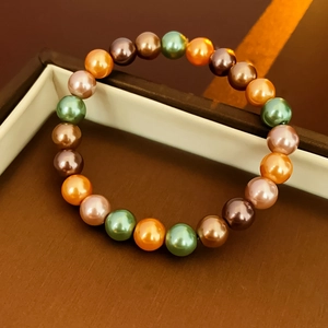 Gros plan d'un bracelet de perles colorées aux teintes de vert vintage et d'orange vif