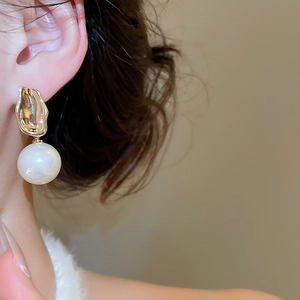 Detail of a French-style gold pleated earring with a large lustrous round pearl on a model