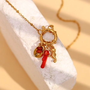 Macro detail of 18K gold plated necklace with red shell and seahorse pendants