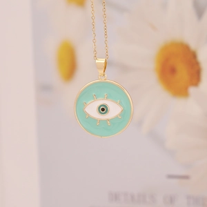 Macro shot of gold 18K evil eye pendant featuring turquoise enamel and eye motif