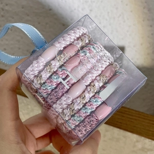 Detailed shot of braided elastic hair ties in a transparent gift box with a blue handle