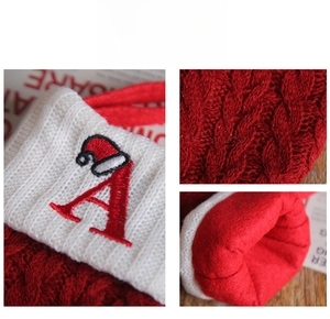 Detail of red cable-knit Christmas stocking with white cuff and red letter A embroidery