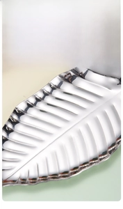 Close-up of golden leaf-shaped stainless steel tray with non-slip vein texture