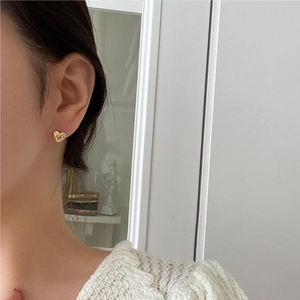 Close-up of heart-shaped gold stud earring with sparkling zircon on model ear
