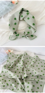 Detail of light green silk scarf with polka dots tied in a knot and laid flat