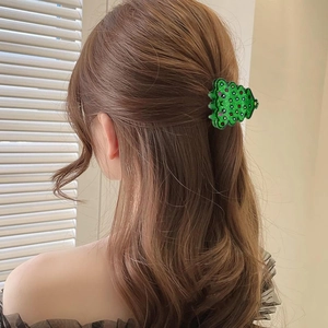 Rear view of a model wearing a green glittery Christmas tree hair claw with red dot accents