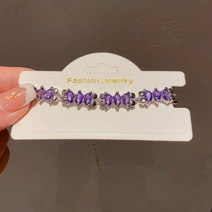 Macro detail of French style silver bracelet featuring oval purple gemstones and claw setting