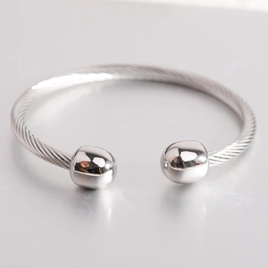 Macro shot of silver stainless steel cable cuff bracelet featuring polished sphere ends