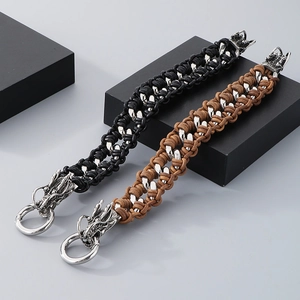 Detail of dragon head clasps on black and brown braided leather bracelets in industrial style