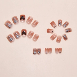 Flat lay of 24 gradient brown press-on nails featuring heart and floral glitter patterns