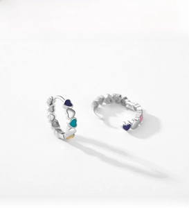 Detail of S925 silver hoop earrings with colorful enamel hearts in a minimalist style