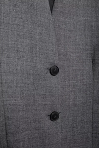 Close-up of grey blazer showing woven fabric texture and black four-hole buttons detail