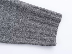 Détail des poignets en tricot côtelé gris montrant la texture douce du tissu en laine