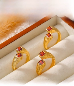Detailed macro view of PVD plated gold rings with square red stones and spiral texture