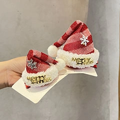 Detail of two red plaid Christmas hat hair clips with white fur trim and silver snowflakes