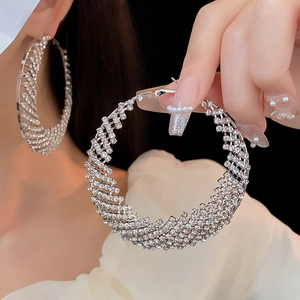 Detailed view of large silver circle earrings with white rhinestones on a model