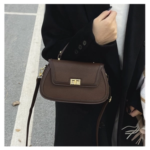 Détail d'un sac à main vintage avec boucle dorée et bandoulière en cuir en extérieur