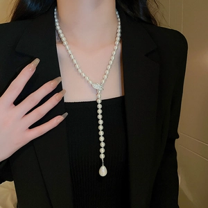 Detail of Y-shaped necklace with white pearls, zircon leaf motif and teardrop pendant