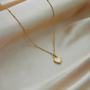 Detail of 18K gold-plated heart necklace with mother-of-pearl inlay on beige silk