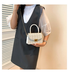 Détail du tissu en tweed blanc avec chaîne en métal doré et boucle sur le sac carré