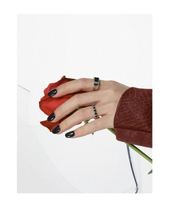 Minimalist silver rings with black accents styled with a red rose for artistic detail